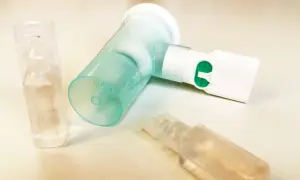 Nebulizator z zielonym przyciskiem i ampułkami, jedna z nich zawiera roztwór NaCl 0,9%.